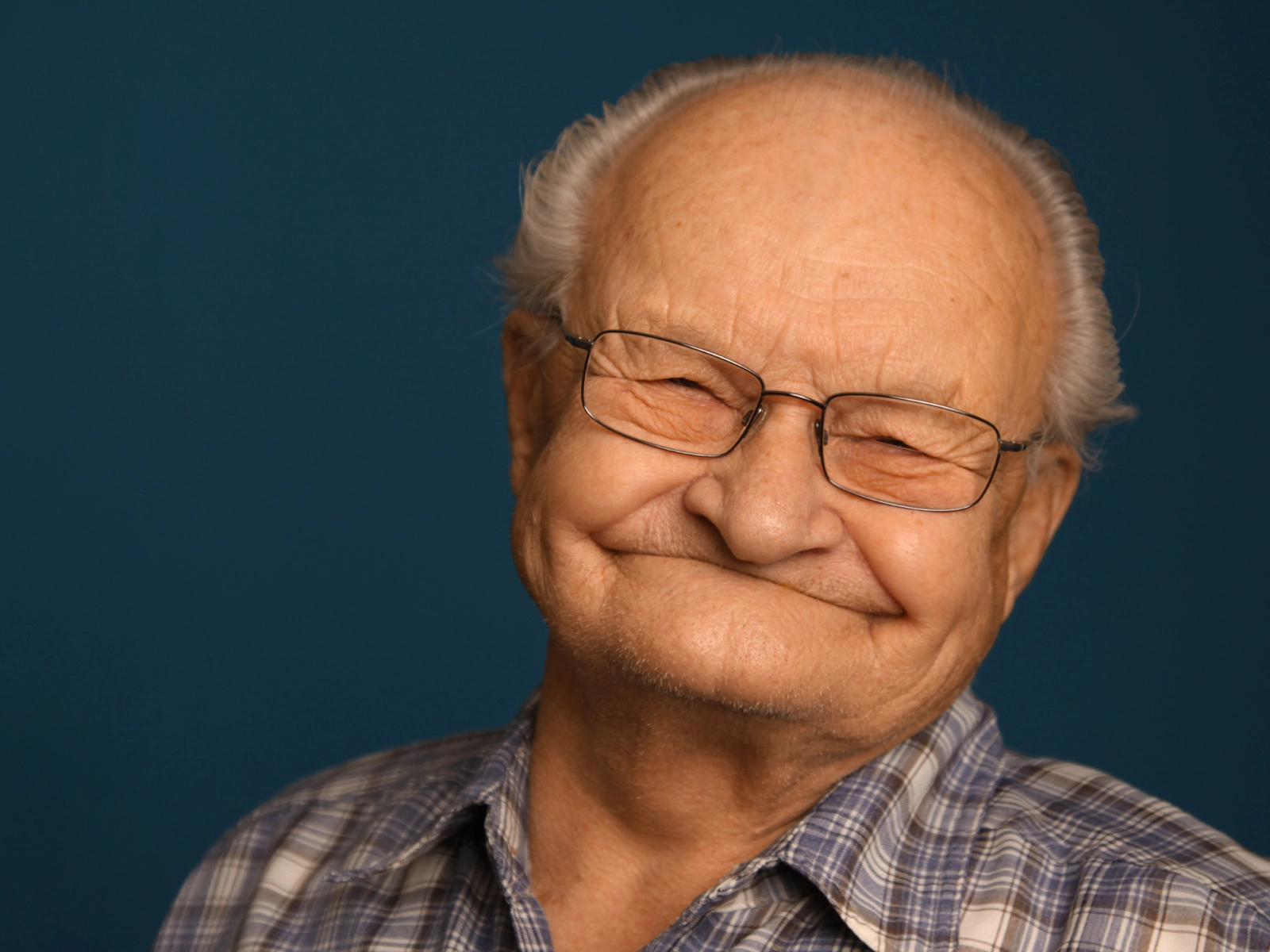 Homme âgé souriant sur un fond uni bleu foncé